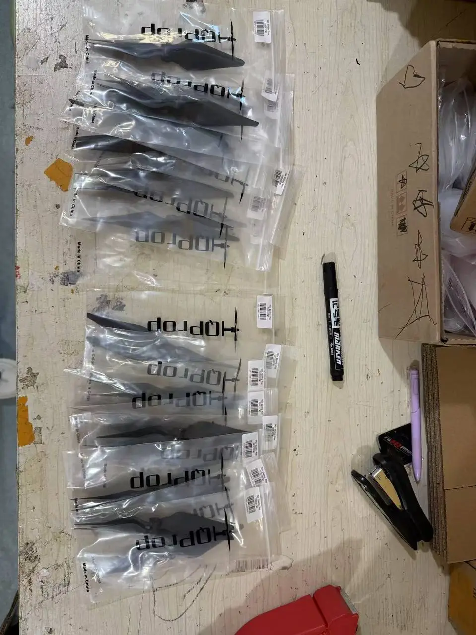 Carbon drone propellers in individual bags laid out on a table before shipment from China
