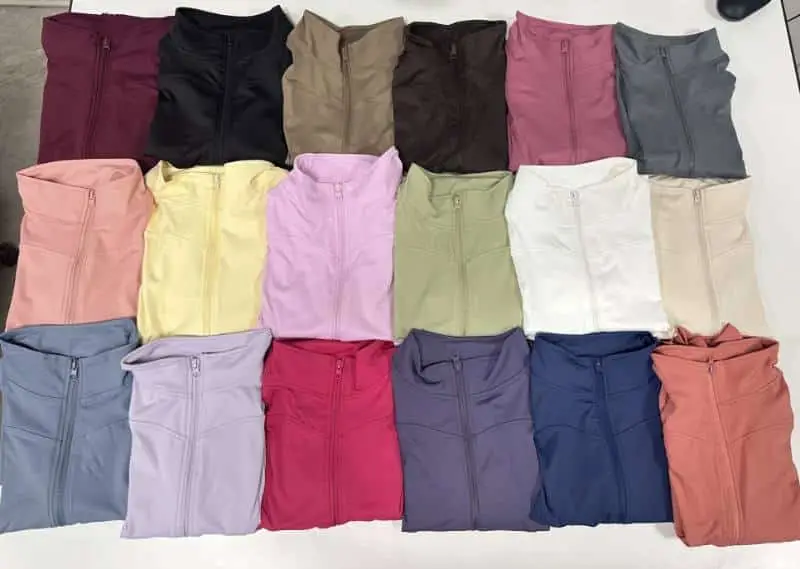 Zip-up sports jackets in different colours laid out for inspection at a clothing factory in China